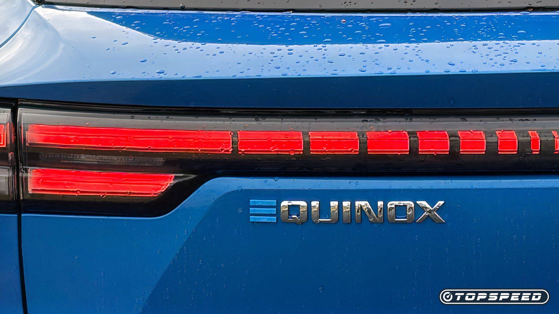 Close-up of a blue Chevrolet Equinox EV rear taillight and Equinox badge with water droplets on the paint.