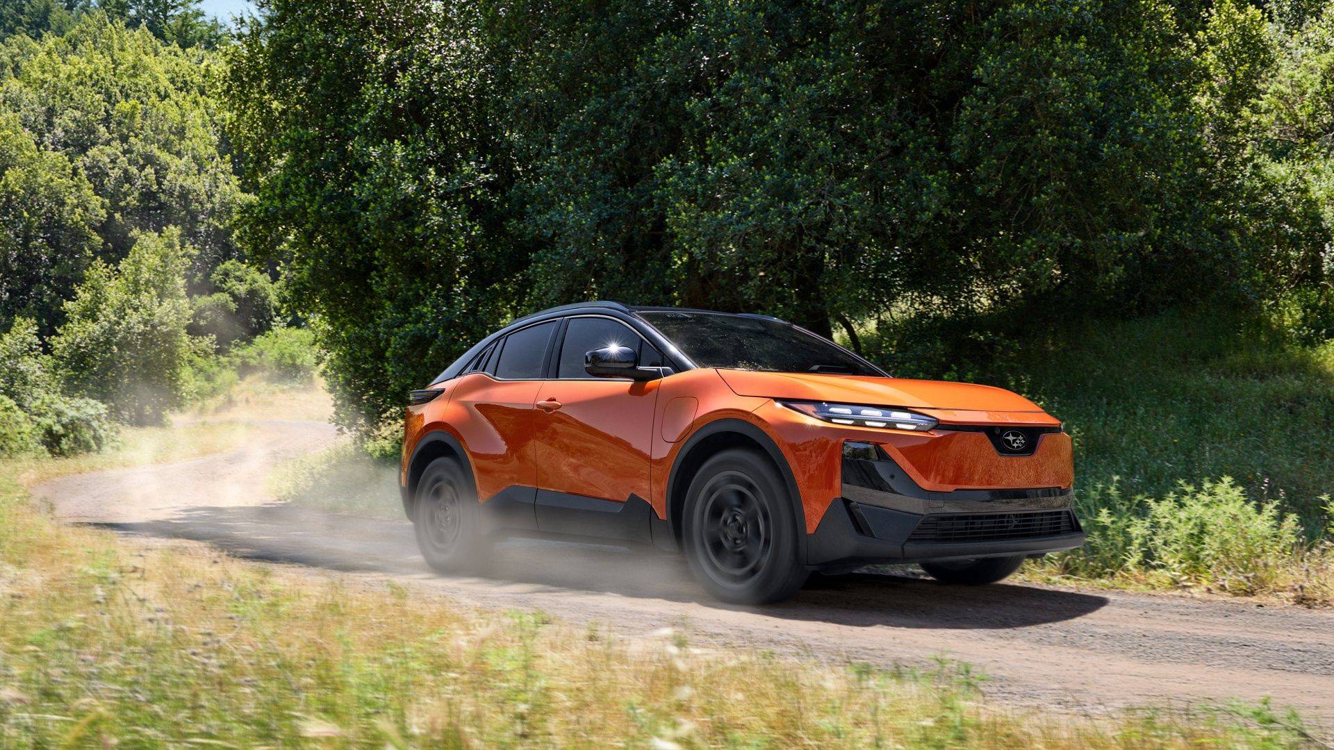 Orange 2026 Subaru Uncharted driving on a dusty rural road through trees