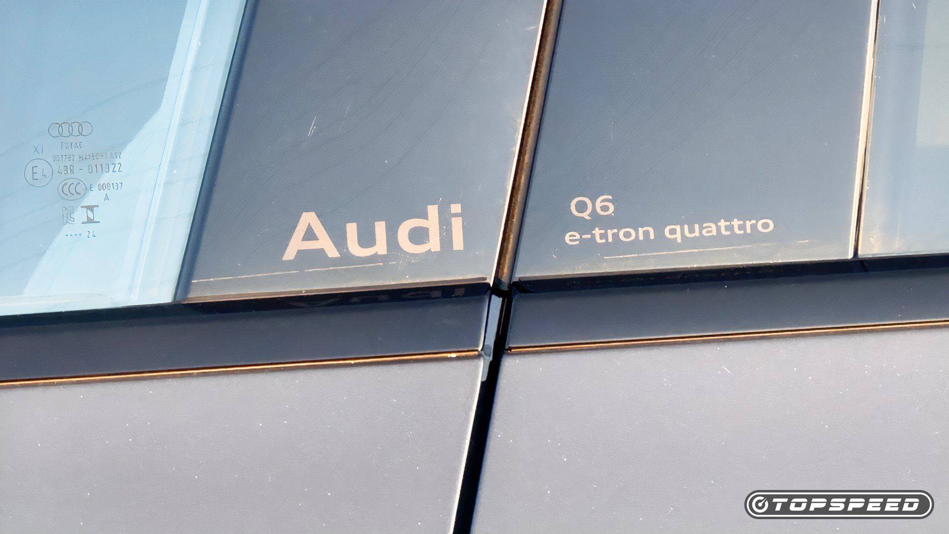 Close-up of Audi Q6 e-tron quattro lettering on a vehicle window and side pillar