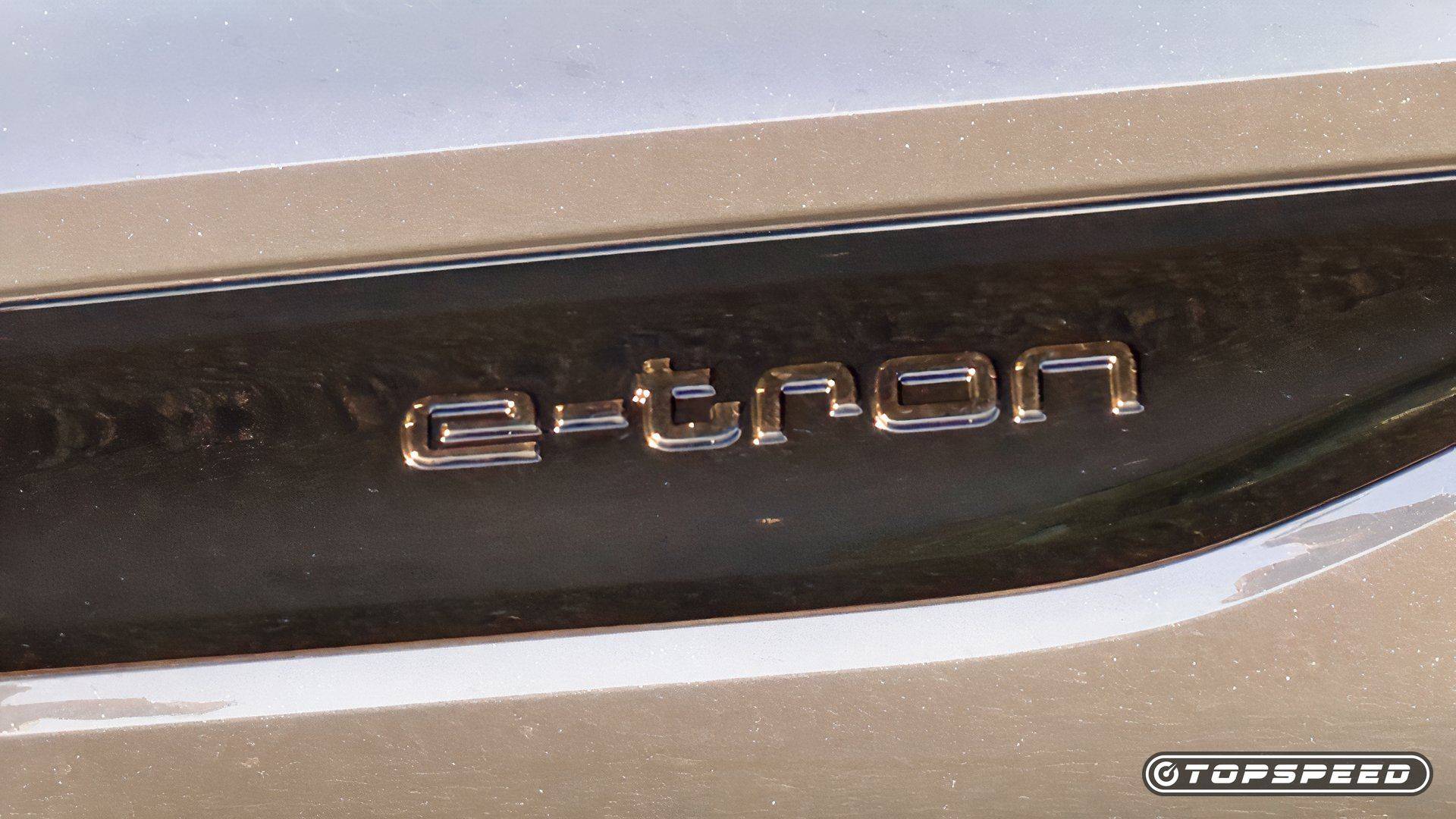 Close-up of an Audi e-tron badge on glossy black vehicle trim