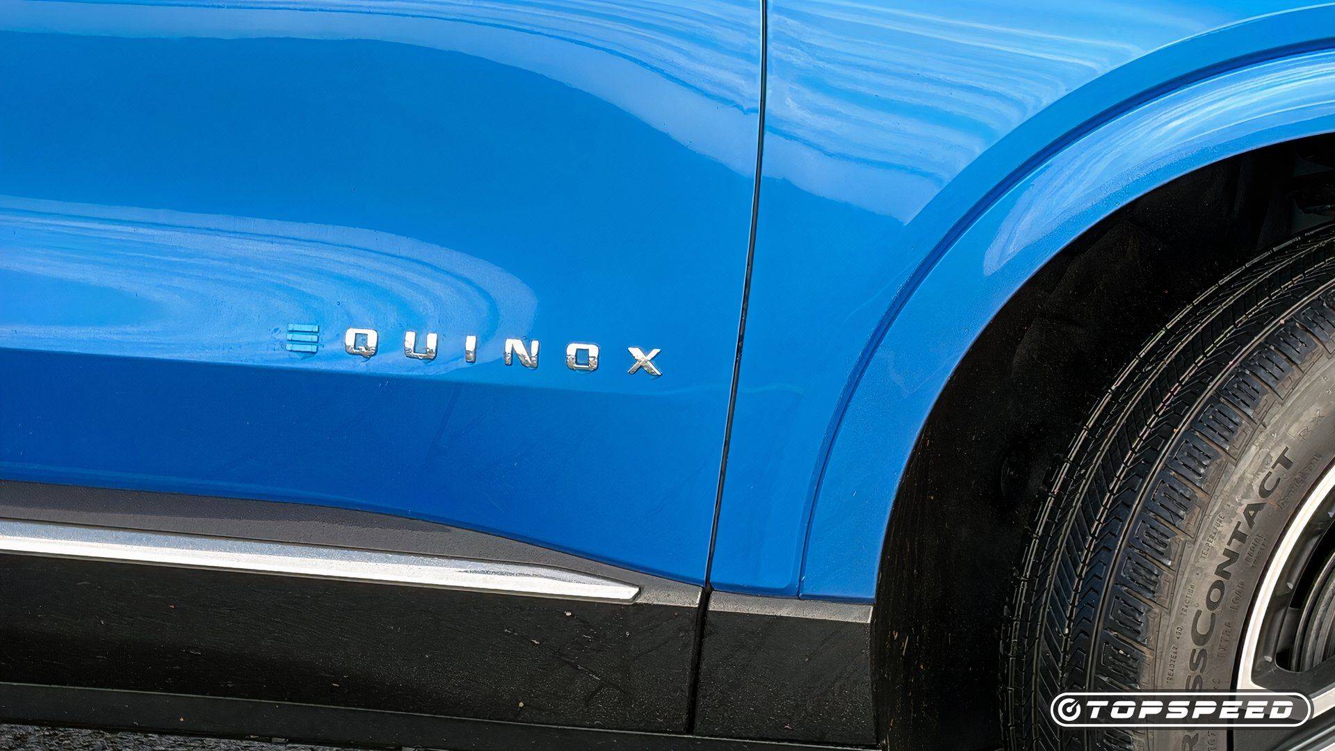 Close-up of a chrome Equinox badge on a blue Chevrolet vehicle beside the front wheel.
