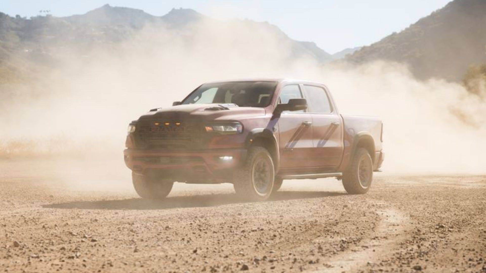 Red Ram 1500 driving through dust on a desert road