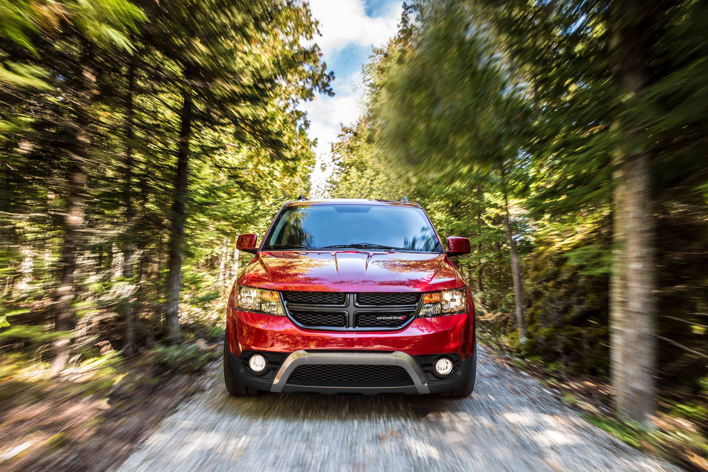 Side profile of a red 2018 Dodge Journey SUV in a field