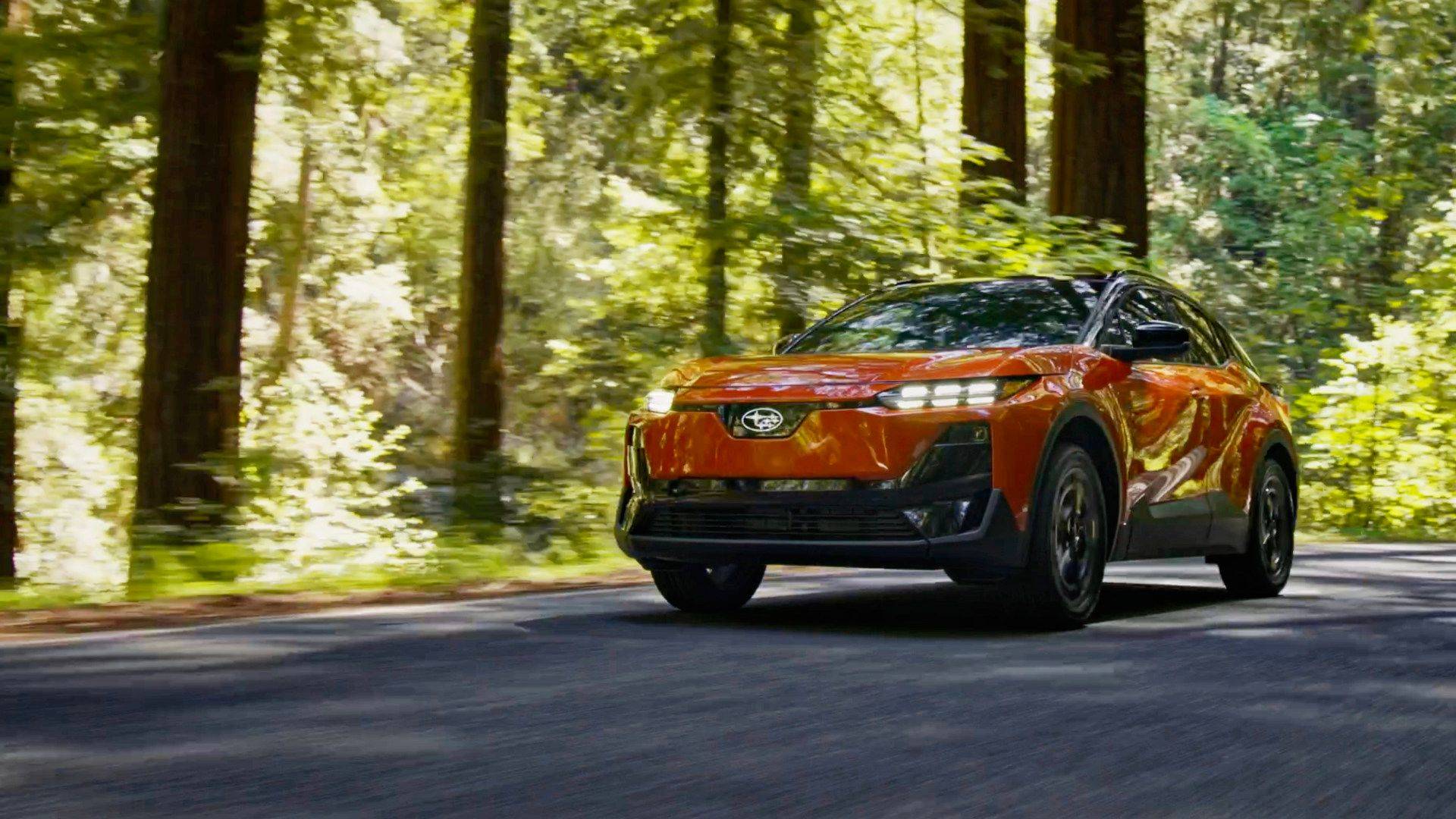 Orange Subaru Uncharted driving through a sunlit forest road