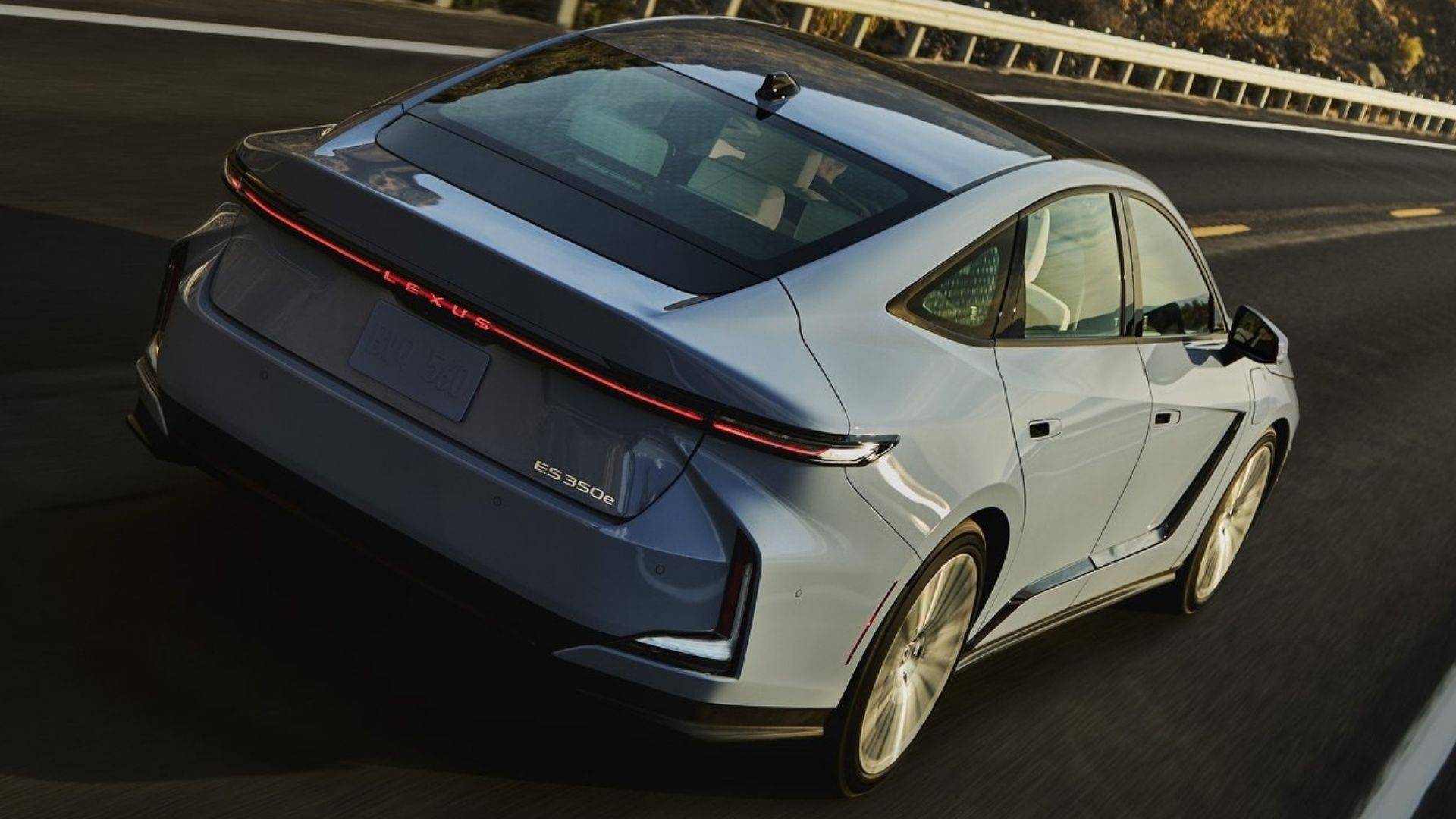 2026 Lexus ES 350h driving on a road from a rear three-quarter angle
