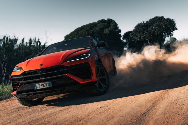 Red Lamborghini Urus SE driving on a dirt road