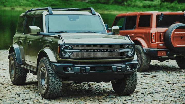 Green and copper Ford Bronco Filson SUVs on a stony riverbed