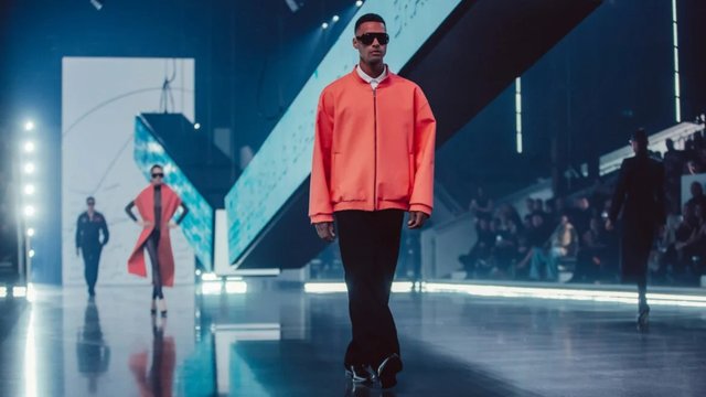 Model in a coral jacket walking in a BRABUS fashion runway presentation