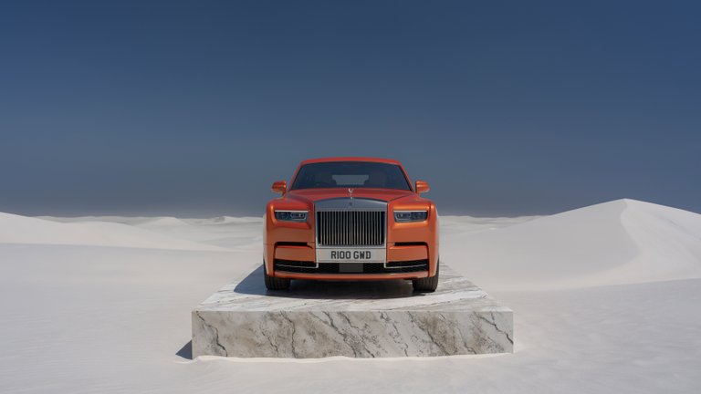 Orange Rolls-Royce Phantom shown from the front in a desert setting