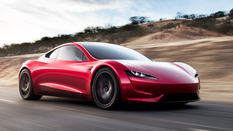Red Tesla Roadster concept driving on a road through dry hills