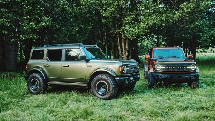 Olive green and copper Ford Bronco Filson SUVs parked beneath trees