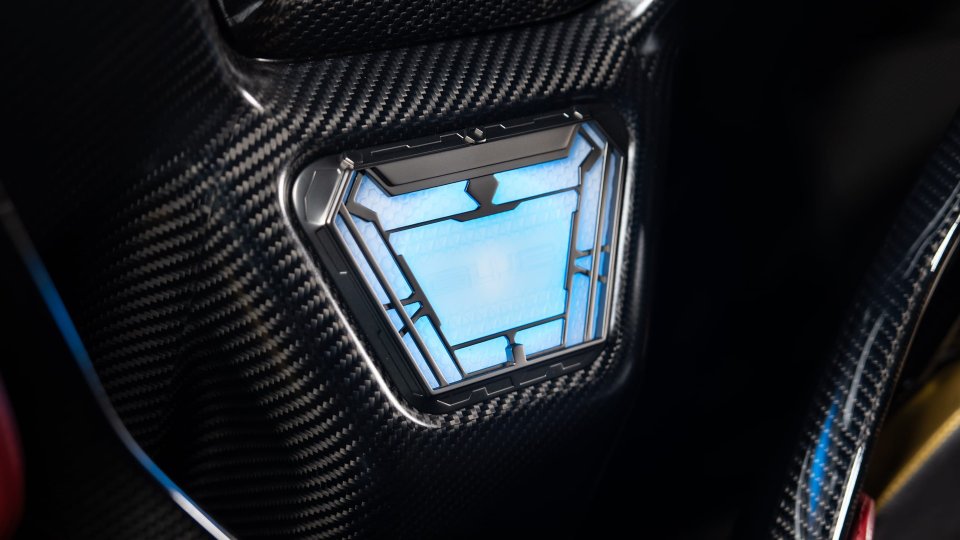 Blue arc-reactor-inspired Gunther Werks badge set into carbon-fiber trim