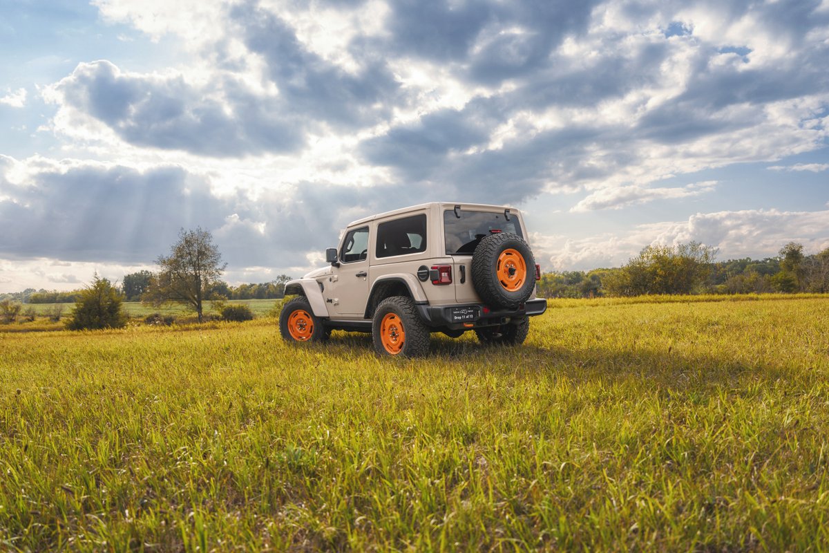 2027 Jeep Wrangler JL-2A shown from the rear in a grassy field with orange wheels