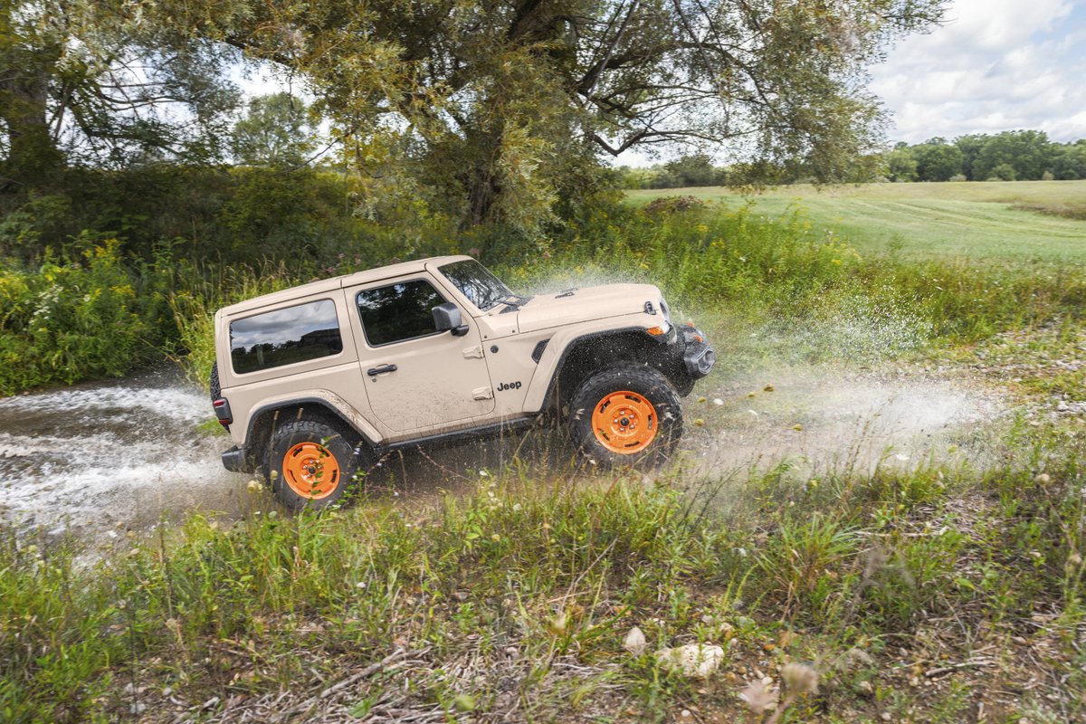 2027 Jeep Wrangler JL-2A driving through a shallow stream with orange wheels