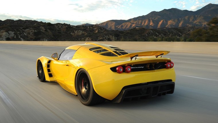 Yellow Hennessey Venom GT driving on a mountain road