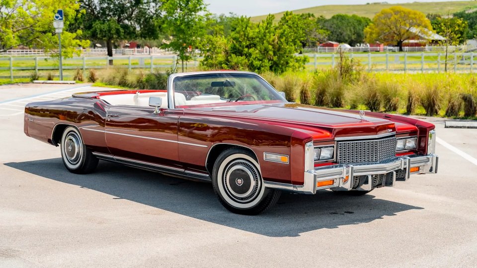 Burgundy 1976 Cadillac Eldorado convertible parked beside a rural property