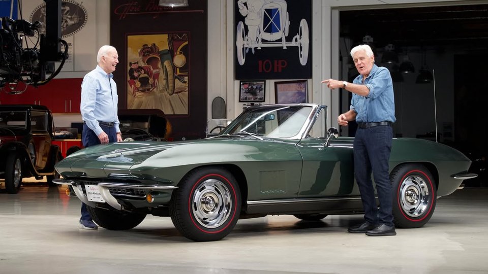 Jay Leno and Joe Biden standing beside a green Chevrolet Corvette in Leno's garage