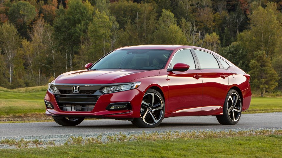 Red Honda Accord Sport parked beside a wooded landscape
