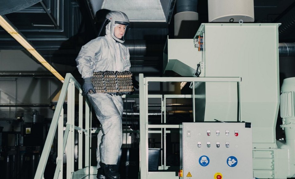 Worker handling a battery module at a battery recycling facility