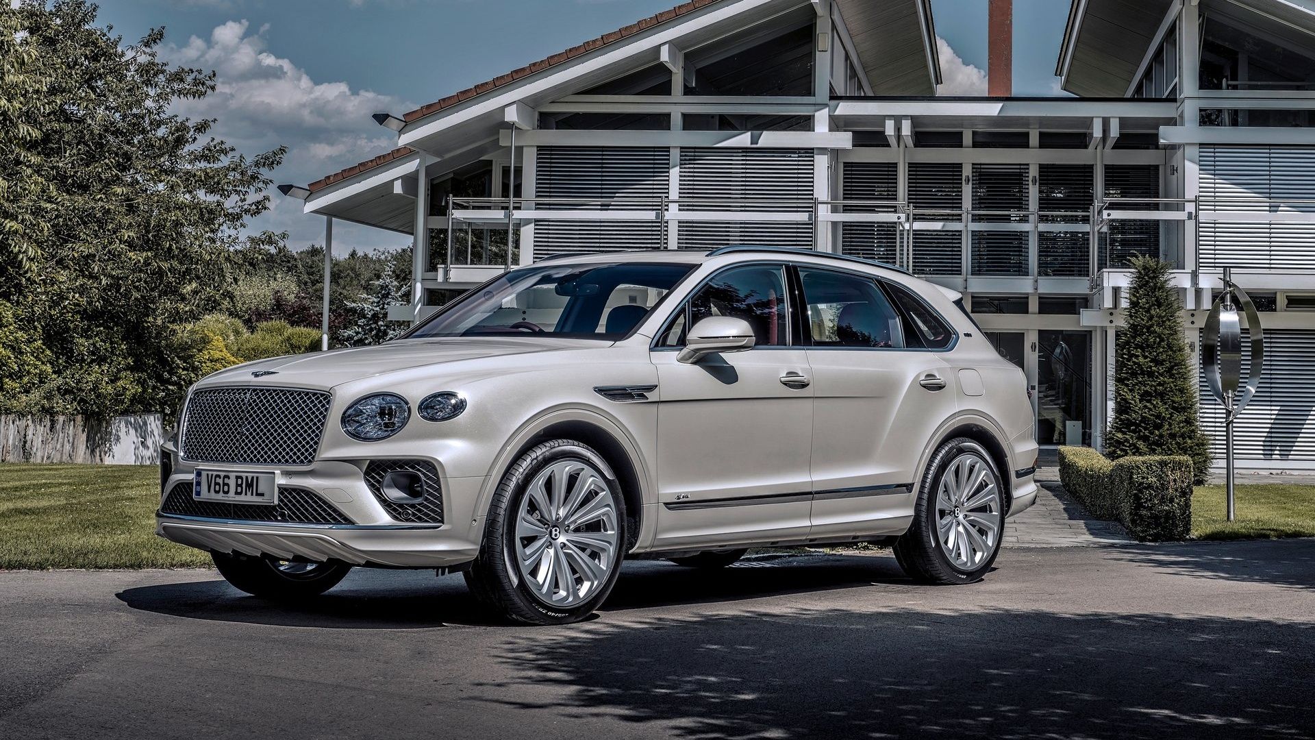 White Bentley Bentayga Hybrid parked beside a modern building