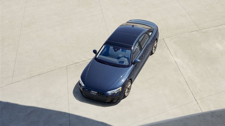 Dark blue Audi A8 luxury sedan parked on a concrete plaza