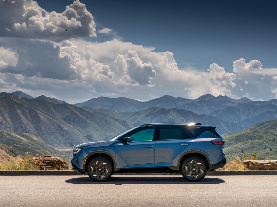 Blue-gray 2027 Nissan Rogue Hybrid in profile against a mountain landscape