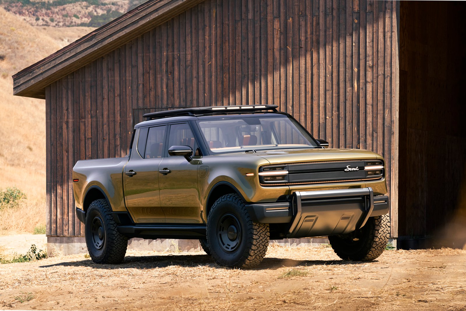 Scout Terra electric pickup truck beside a wooden barn