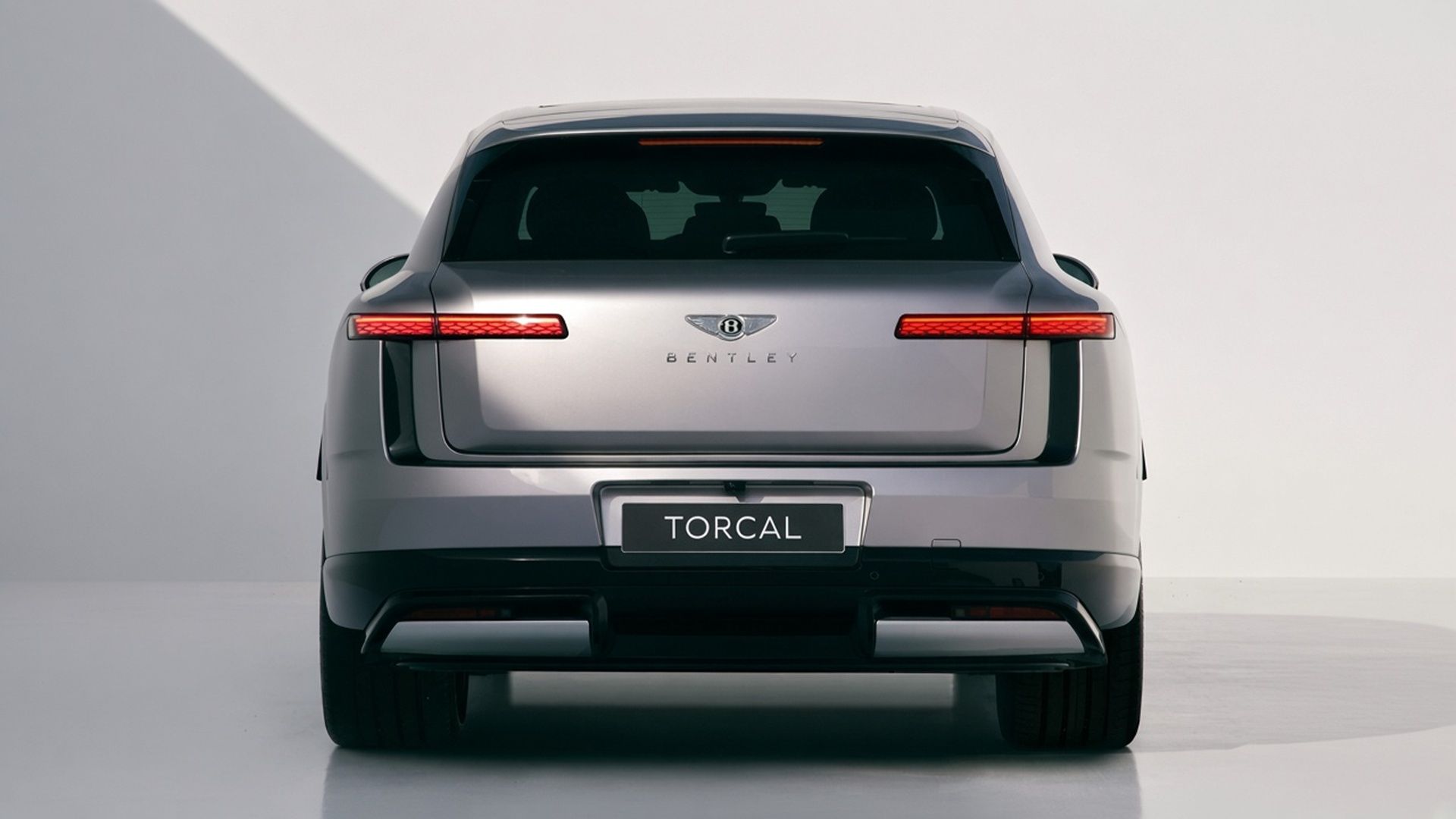 Silver Bentley Torcal electric SUV viewed from the rear in a studio