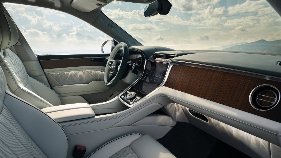 Light leather Bentley Torcal interior with wood trim and a large curved center touchscreen