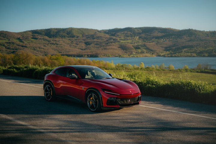 Red Ferrari Purosangue on a country road beside a lake