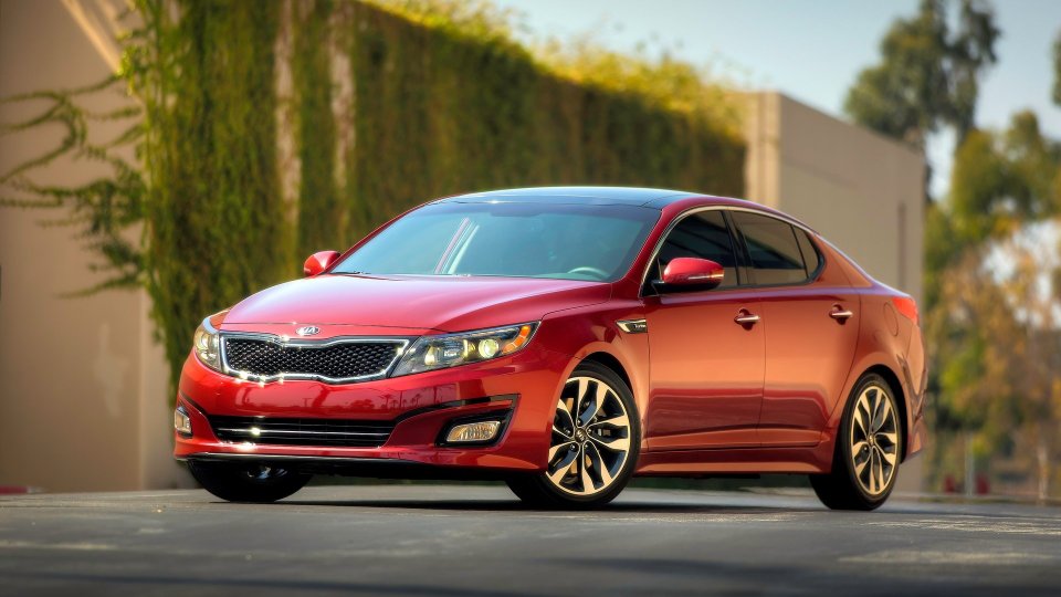 Red Kia Optima sedan on a sunlit street