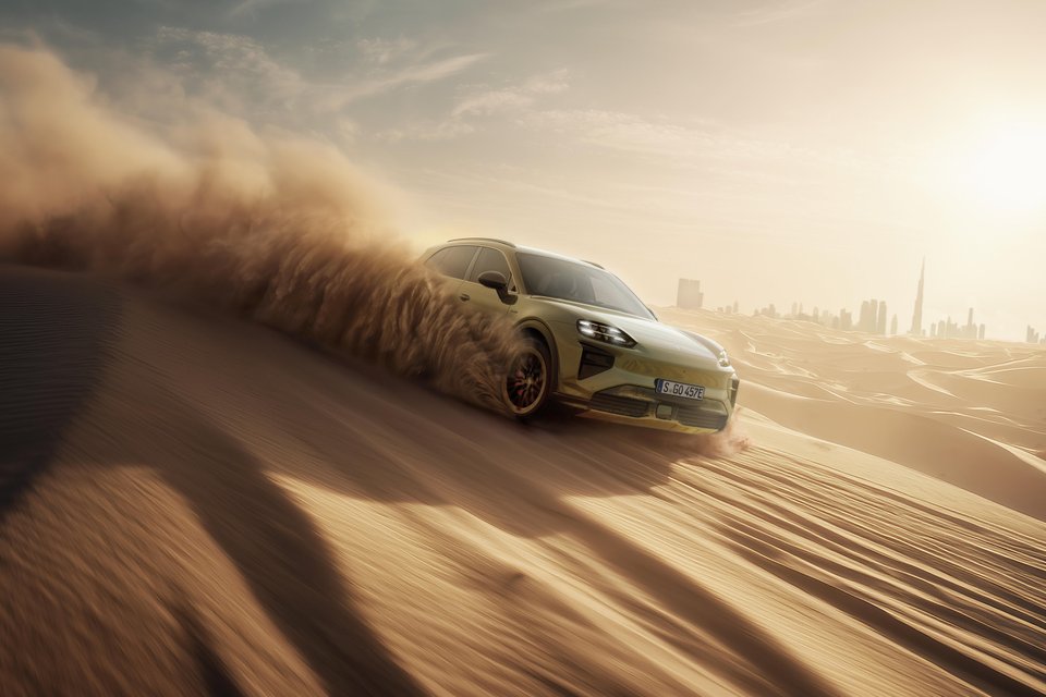 Green Porsche Cayenne Electric driving through desert dunes