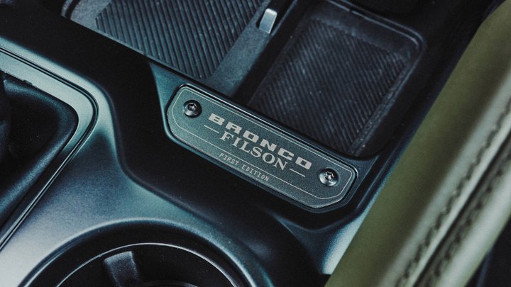 Serialized Bronco Filson First Edition badge beside a center-console cup holder