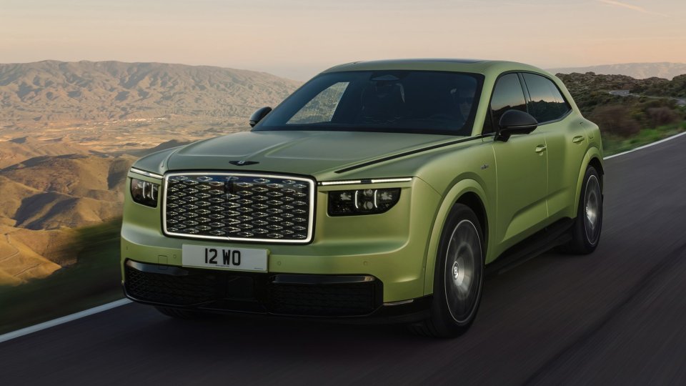 Green Bentley Torcal electric SUV driving through a mountainous landscape at dusk